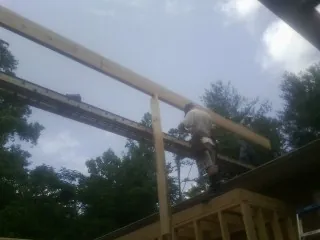 Carpenter setting a ridge beam over a new addition frame — Ice Dam Removal by Roofing Brothers in Milan
