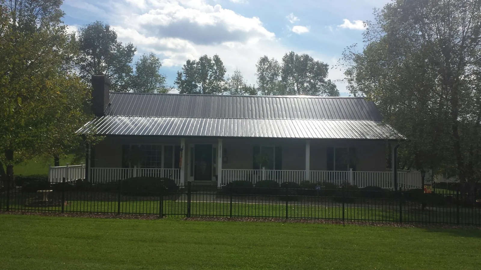 Gray metal roof on a brick ranch with a full width front porch — Gutter Guard Installation work by our crew in Milan